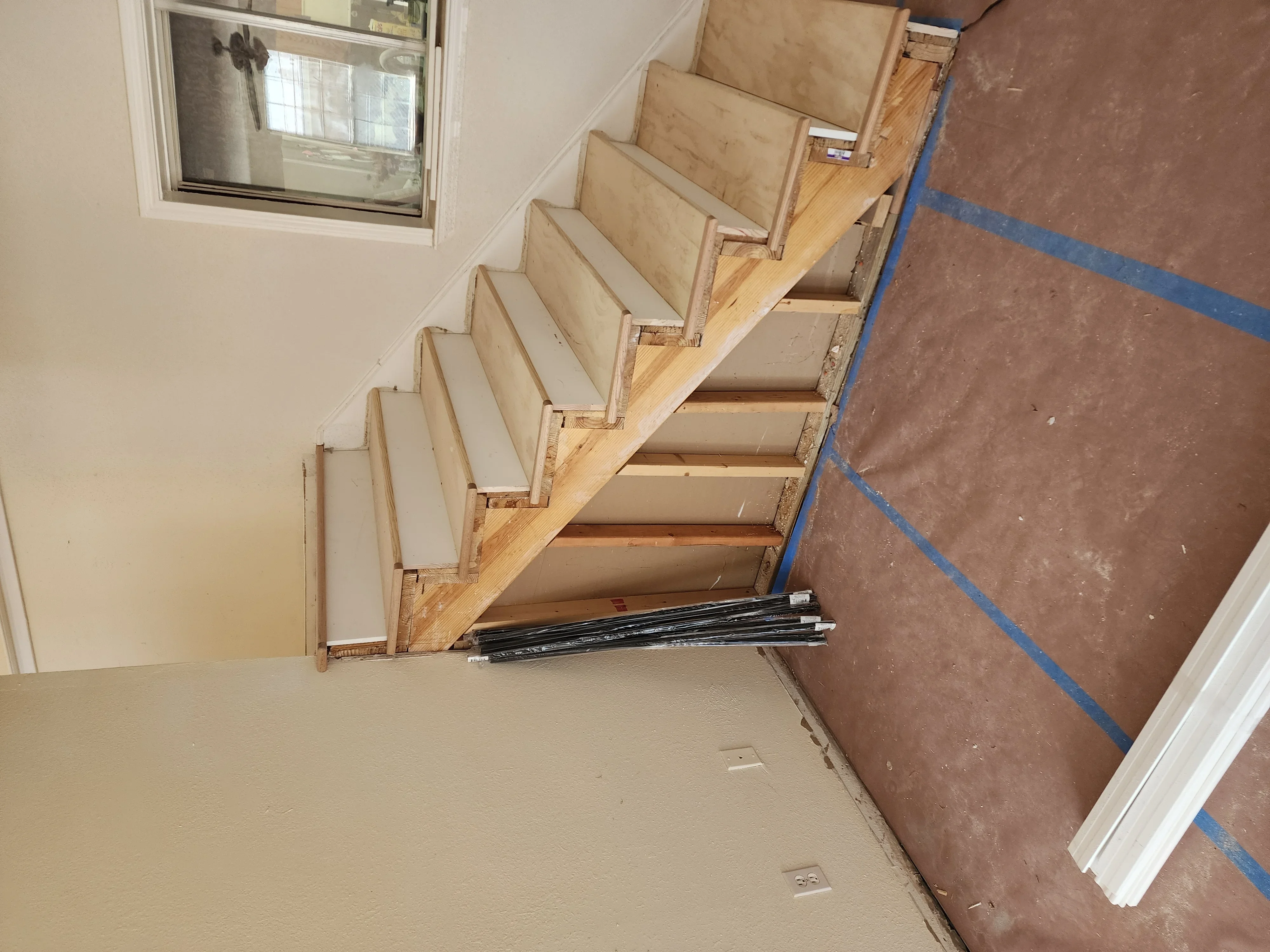 Wooden staircase with painted risers and natural wood treads during installation