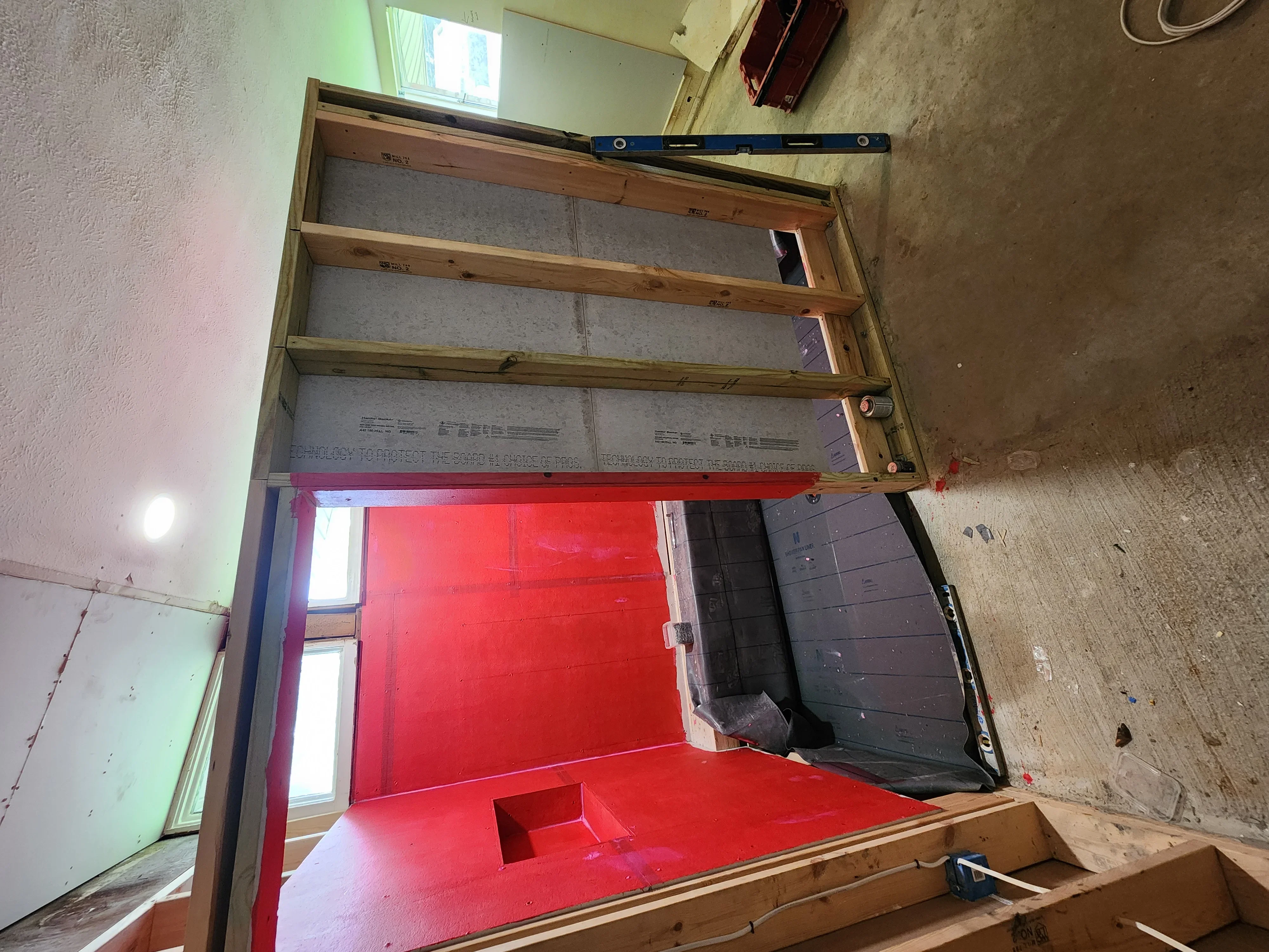 Kitchen remodel framing with wooden studs, insulation, and red cabinet base installation in progress